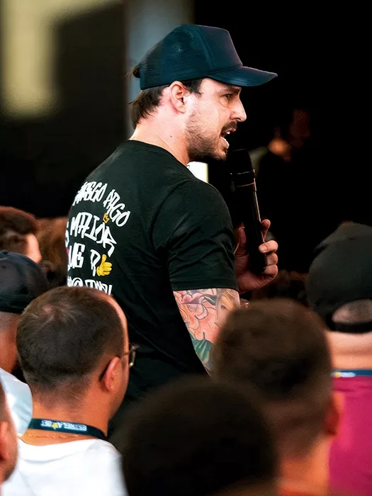 Lucas Viana de microfone na mão, no meio da plateia de um encontro presencial da Comunidade